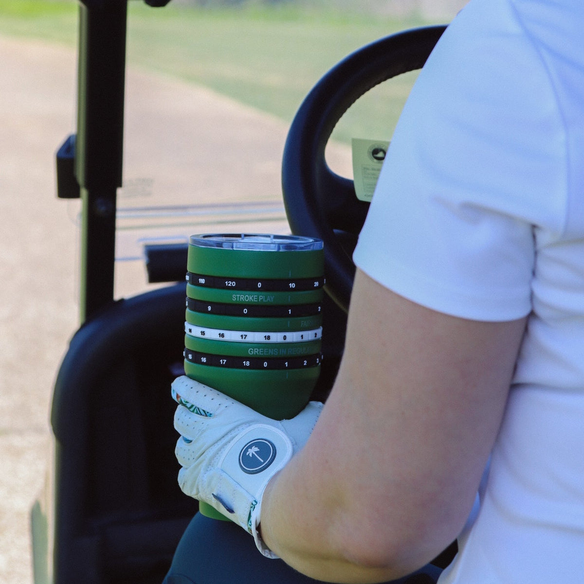 Person holding a green golf club with a white glove on a golf course